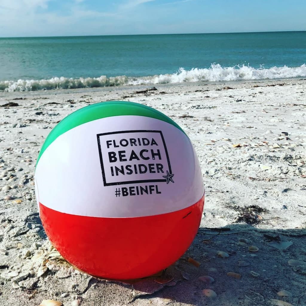 A photo of a beach ball on a beach. The beach ball bears the Florida Beach Insider logo.